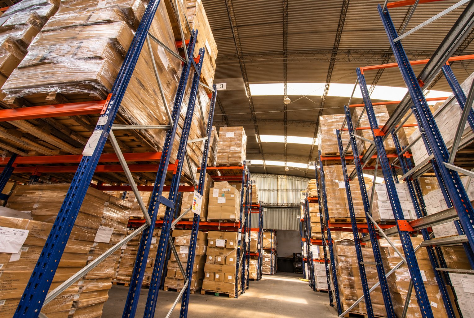 Pasillo entre racks de tres niveles con mercadería paletizada